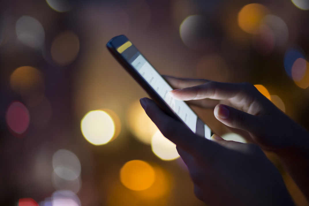 Woman using mobile phone city lights in background